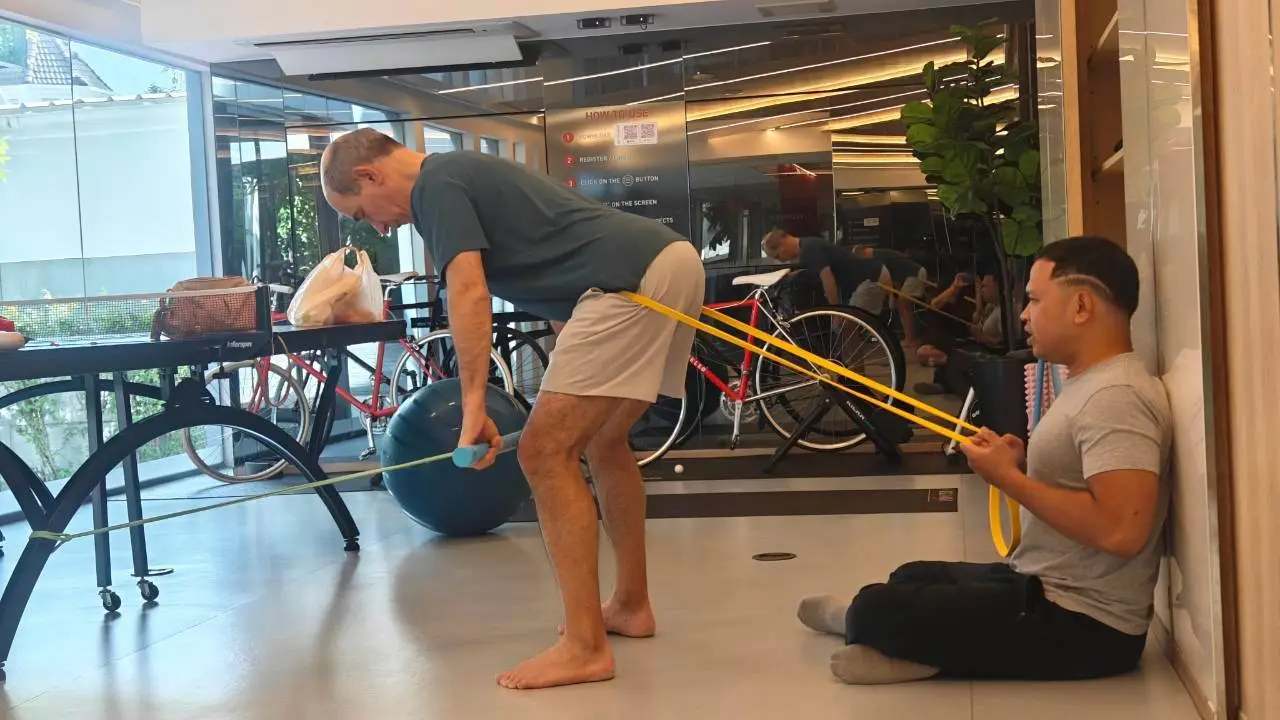 Client doing a banded hip hinge while Boss coaches from the floor