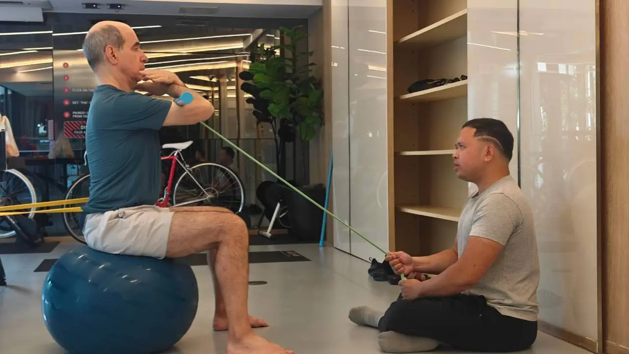 Client doing a banded chest press on a stability ball with Boss holding the band