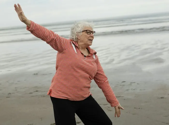 Older woman stretching her arms freely on a beach