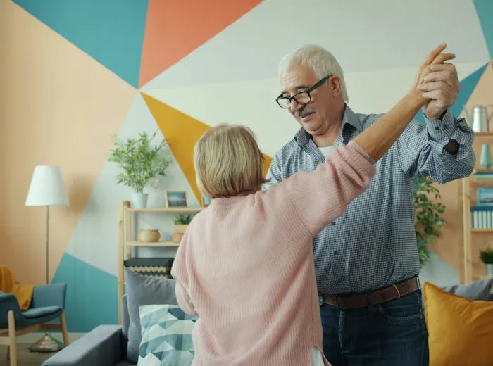 Older couple dancing together in a bright living room